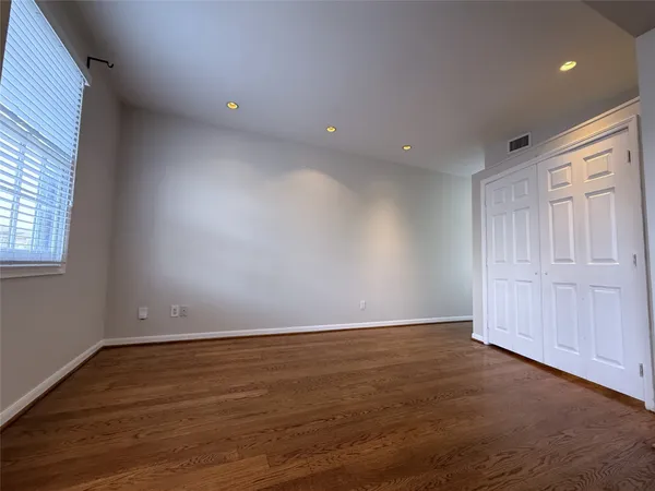 a view of empty room with wooden floor and kitchen