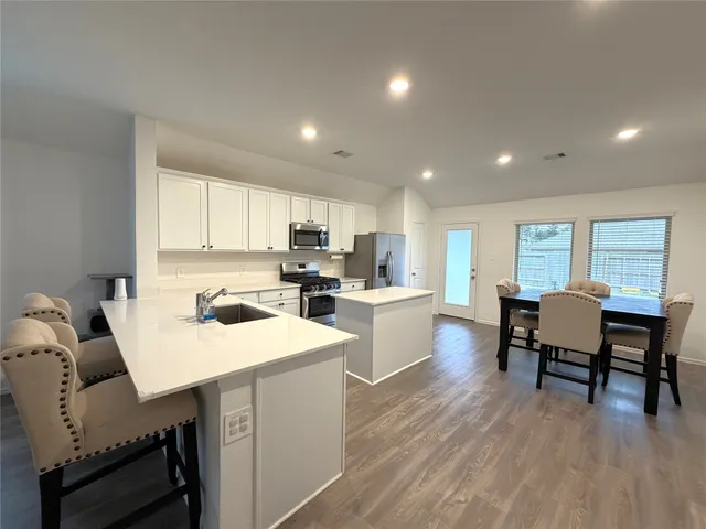 a living room with furniture a dining table wooden floor and a sink