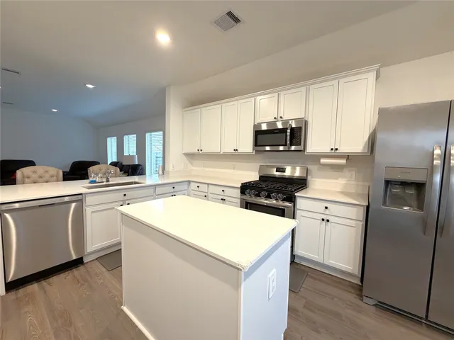 a kitchen with granite countertop a refrigerator stove top oven and sink