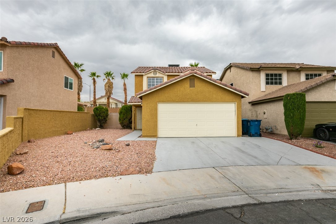 View of front of property featuring stucco siding, concrete driveway, a tile roof, and an attached garage