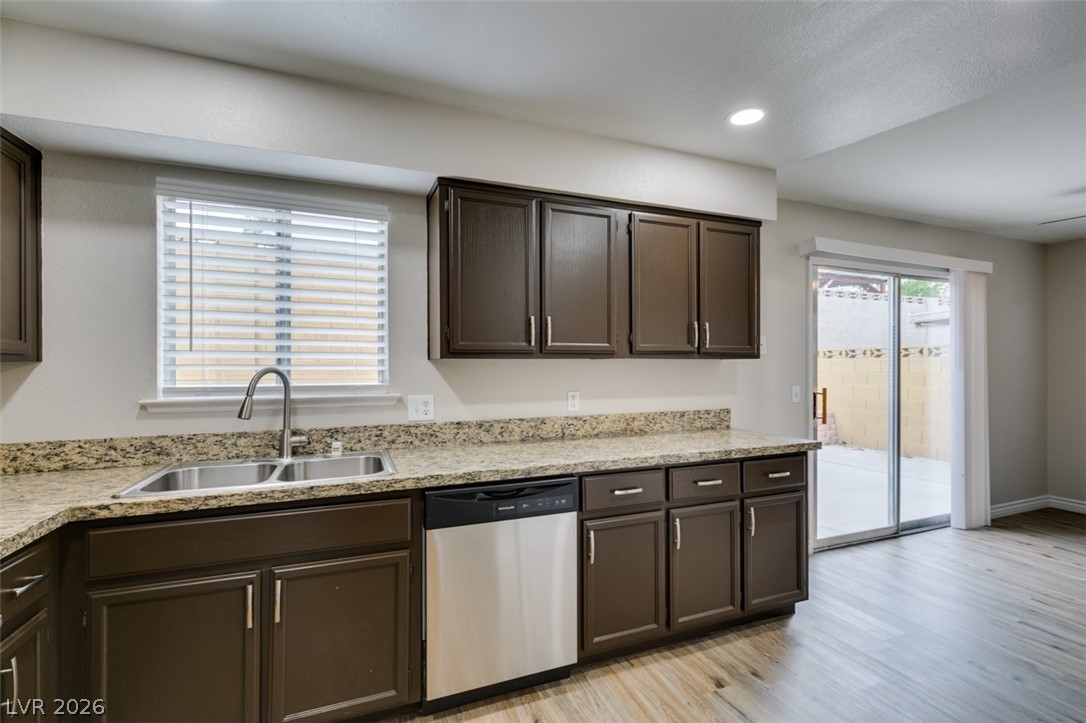 905 Scarlet Ridge Drive Las Vegas, NV 89128 - Photo 21 of 39 Kitchen featuring dark wood finish cabinets, dishwasher, light wood-type flooring, light stone counters, and recessed lighting