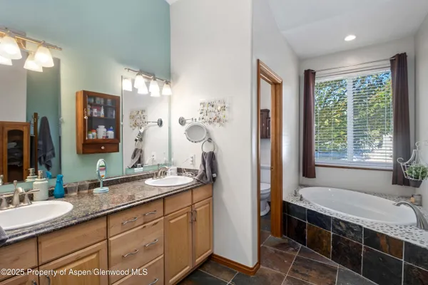 a bathroom with a granite countertop tub a double vanity sink and a large mirror