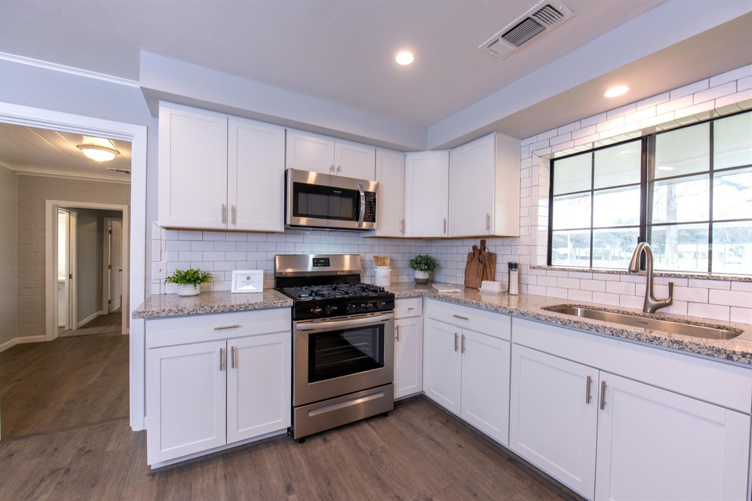 1322 North Reed Avenue Reedley, CA 93654 - Photo 17 of 54 a kitchen with granite countertop white cabinets white stainless steel appliances a sink and a window