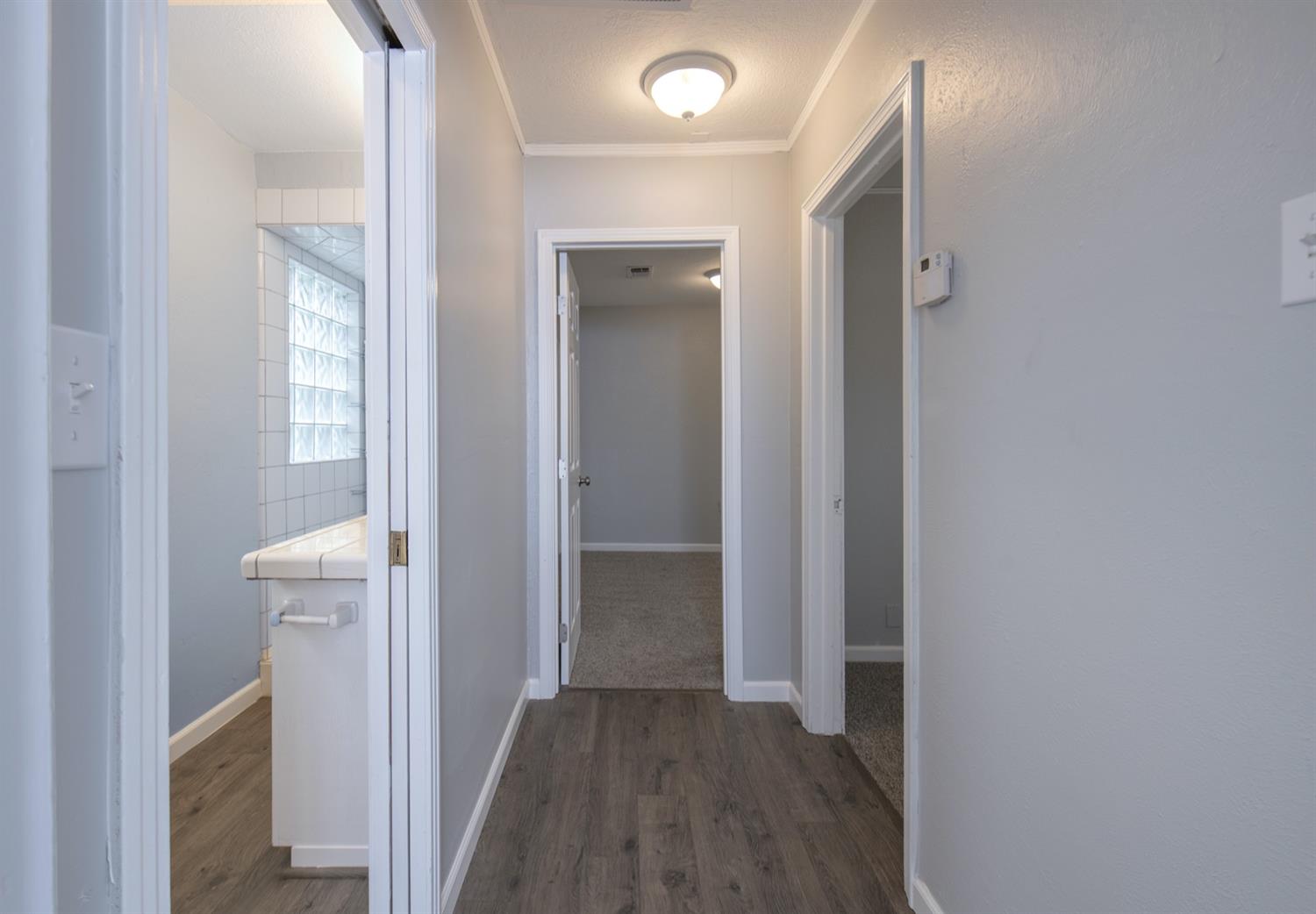 1322 North Reed Avenue Reedley, CA 93654 - Photo 31 of 54 a view of a hallway with wooden floor and a bathroom