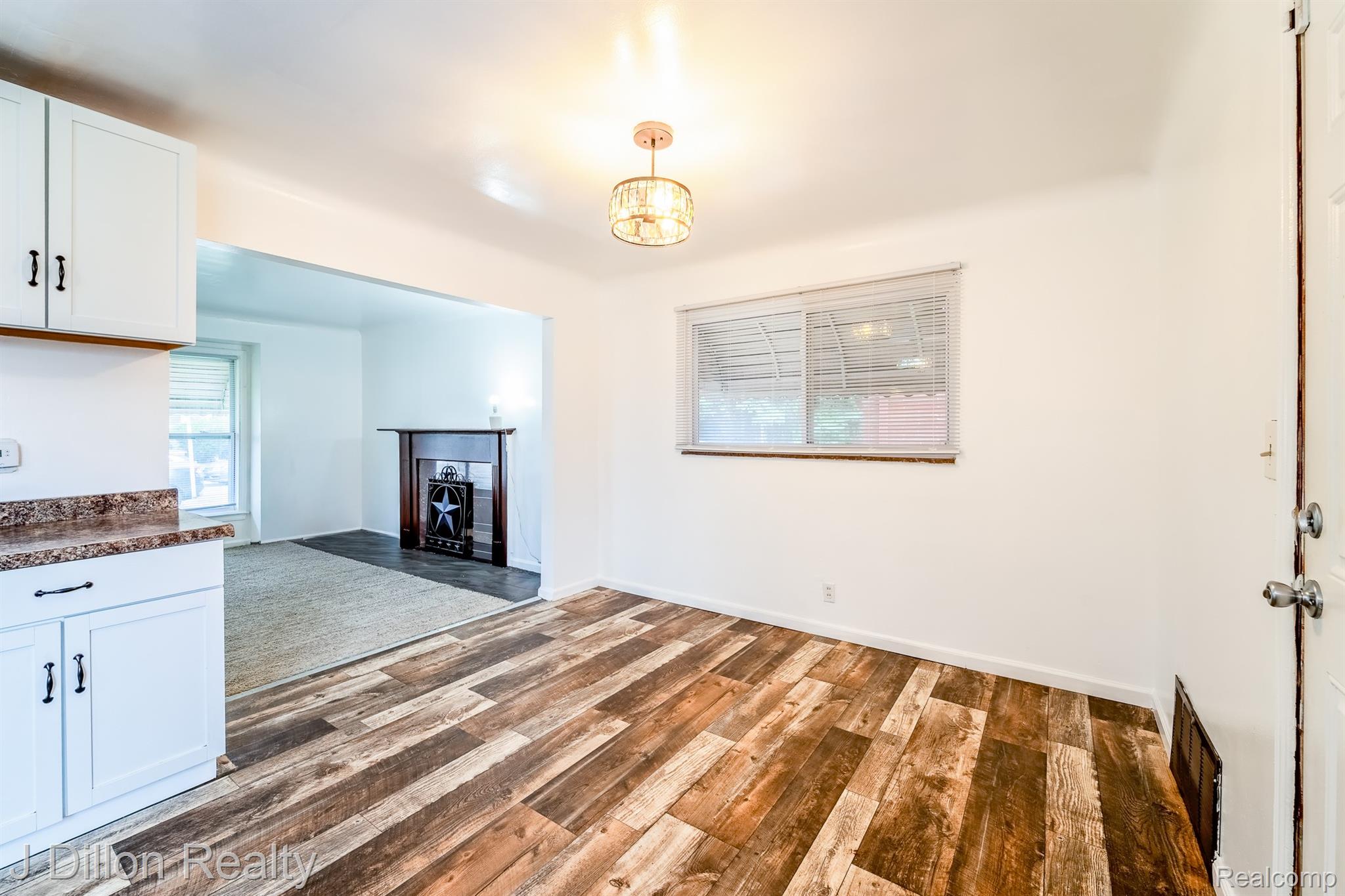 99 Chestnut Street River Rouge, MI 48218 - Photo 15 of 50 Unfurnished living room with dark wood finished floors, a fireplace, and hanging lights