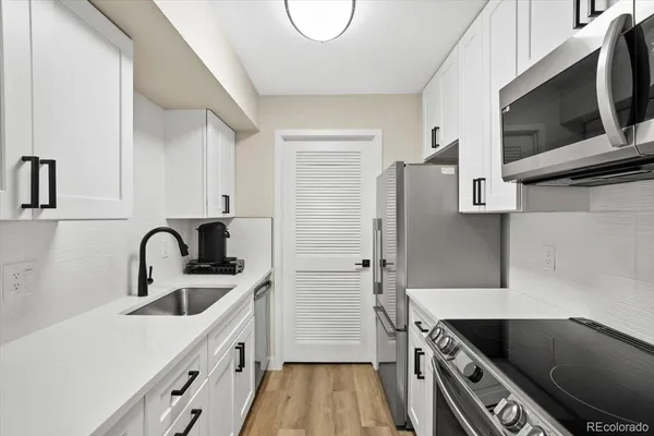 a kitchen with stainless steel appliances a sink a stove and a refrigerator with wooden floor