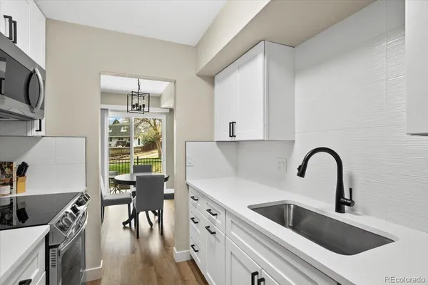 a kitchen with granite countertop a stove a sink a dining table and chairs