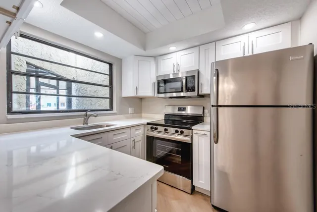 a kitchen with stainless steel appliances granite countertop a refrigerator a stove a sink and a microwave