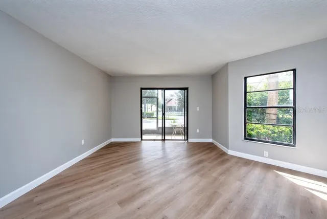 an empty room with wooden floor and windows