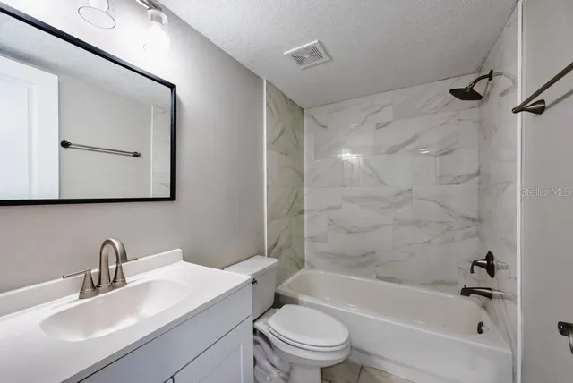 a bathroom with a bathtub shower sink vanity mirror and toilet