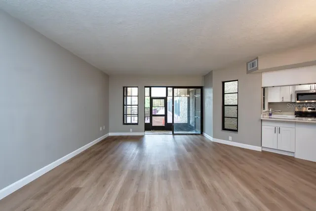 a view of an empty room with window and wooden floor