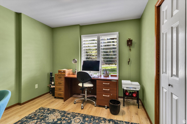 2863 Fallentine Road Sandy, UT 84093 - Photo 26 of 48 Interior room featuring light green walls, wood-finish flooring, a window with plantation shutters, a white paneled bi-fold door with wood trim, and a built-in architectural element