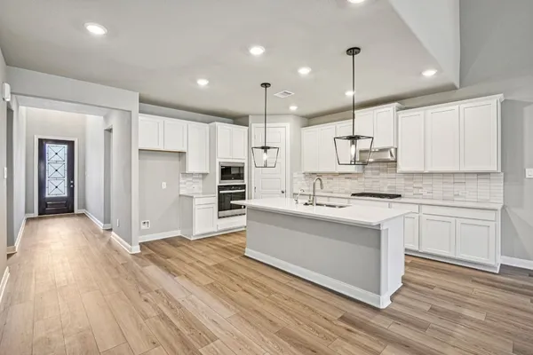 a large kitchen with cabinets wooden floor and stainless steel appliances