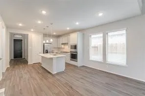 a large kitchen with kitchen island a sink wooden floor and a refrigerator