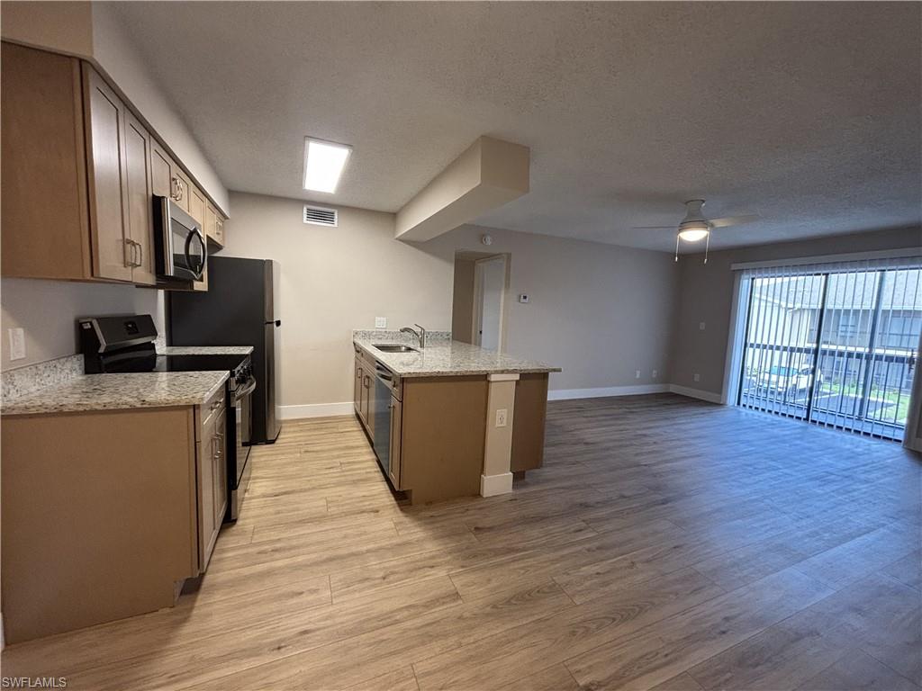5319 Summerlin Road, Unit 1916 Fort Myers, FL 33919 - Photo 3 of 8 a kitchen with stainless steel appliances granite countertop a sink a stove a refrigerator cabinets and wooden floor