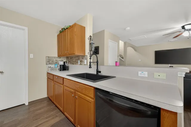 a kitchen with stainless steel appliances a sink dishwasher stove and microwave with wooden floor