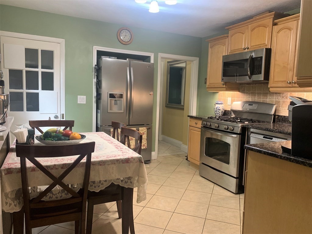 35 5th Street Medford, MA 02155 - Photo 12 of 42 a kitchen with stainless steel appliances kitchen island granite countertop a stove top oven a sink dishwasher a dining table and chairs with wooden floor