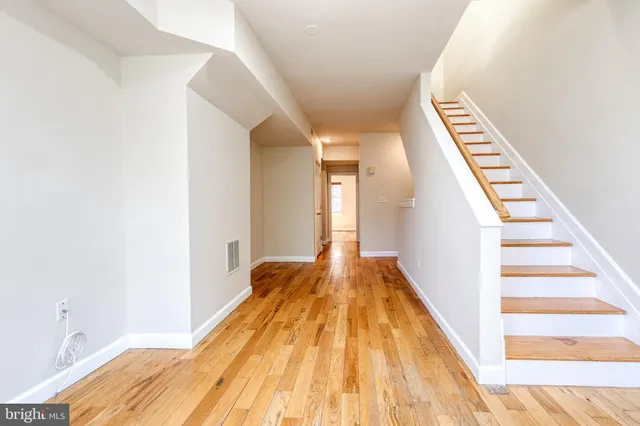 a view of a hallway with wooden floor and staircase