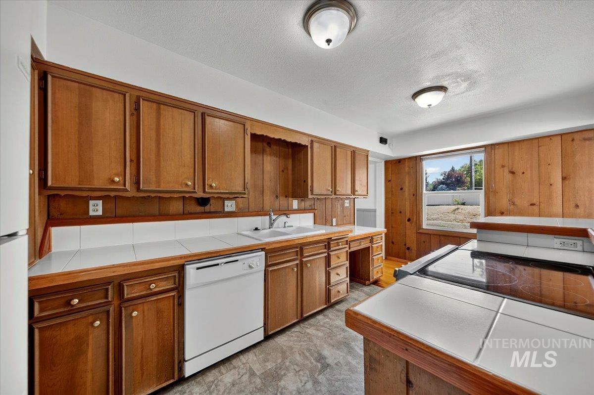 2160 South Five Mile Road Boise, ID 83709 - Photo 18 of 41 Kitchen featuring wood cabinetry, white tile countertops, a built-in dishwasher, and a window providing natural light