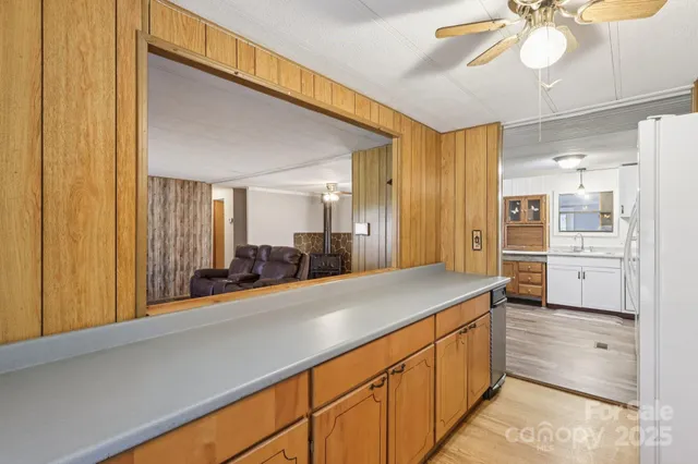 a kitchen with stainless steel appliances granite countertop a refrigerator a sink dishwasher a stove and white countertops with wooden floor