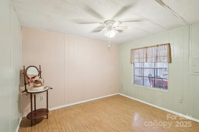 a view of a room with a chandelier fan and wooden floor