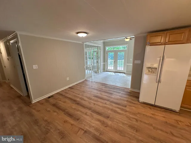 an empty room with wooden floor and a refrigerator