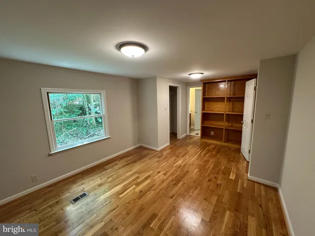 a view of empty room with wooden floor and window