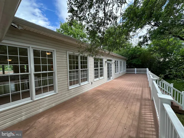 a view of house with deck and a garden
