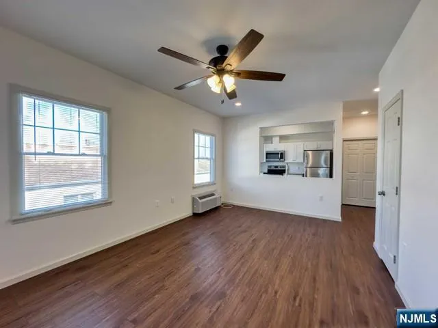 a view of an empty room with window and wooden floor