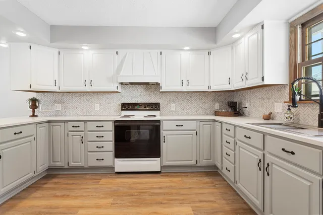 a kitchen with stainless steel appliances granite countertop a stove a sink and white cabinets