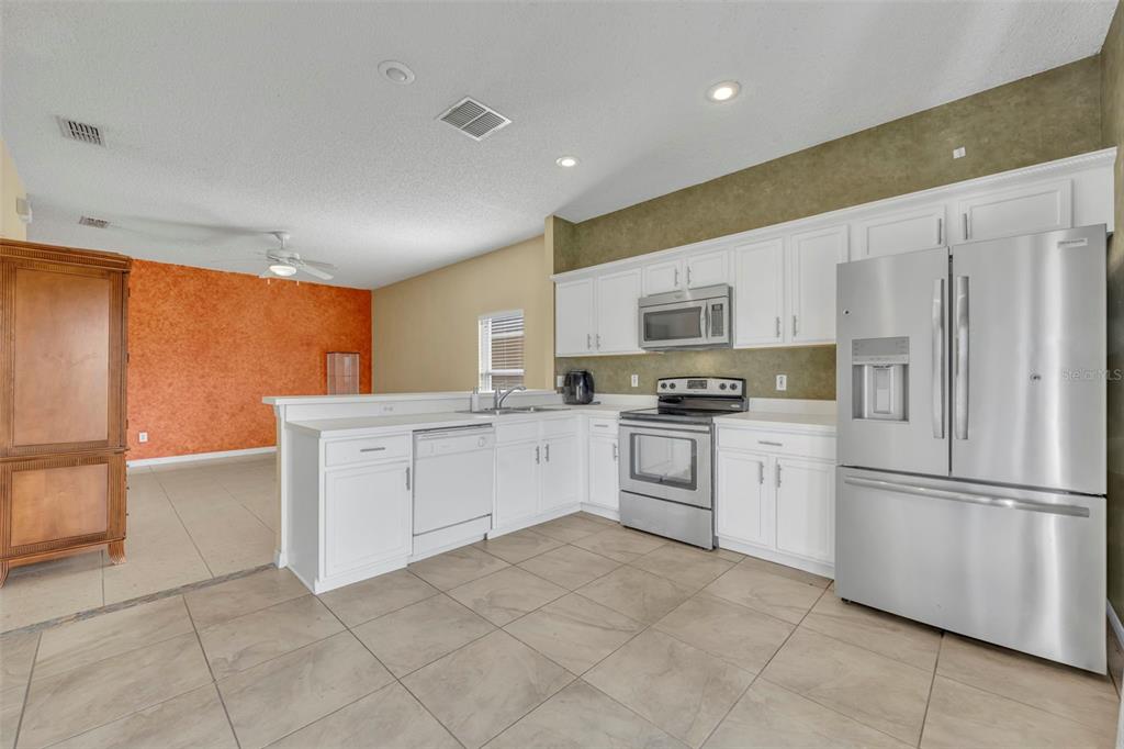 4718 Waterside Pointe Circle Orlando, FL 32829 - Photo 12 of 30 a kitchen with white cabinets and white appliances
