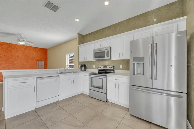 a kitchen with white cabinets stainless steel appliances and a refrigerator