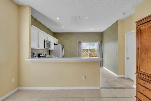 a living room with stainless steel appliances granite countertop a refrigerator and a sink