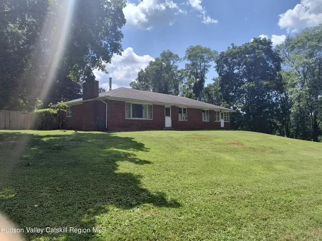 a front view of house with yard and trees in the background