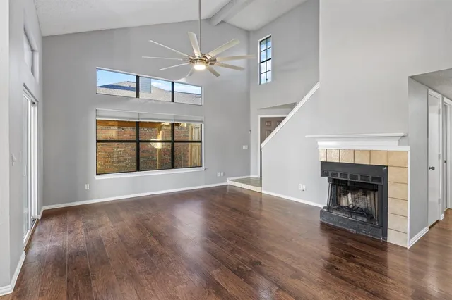 an empty room with wooden floor fireplace and windows