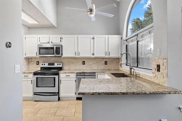 a kitchen with granite countertop a sink stainless steel appliances and white cabinets