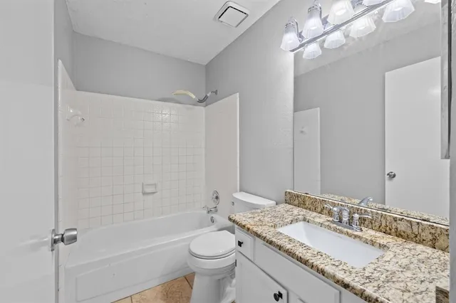 a bathroom with a granite countertop sink a toilet and shower
