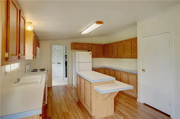 a kitchen with a refrigerator a sink and wooden floor