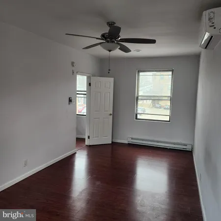an empty room with wooden floor chandelier fan and windows