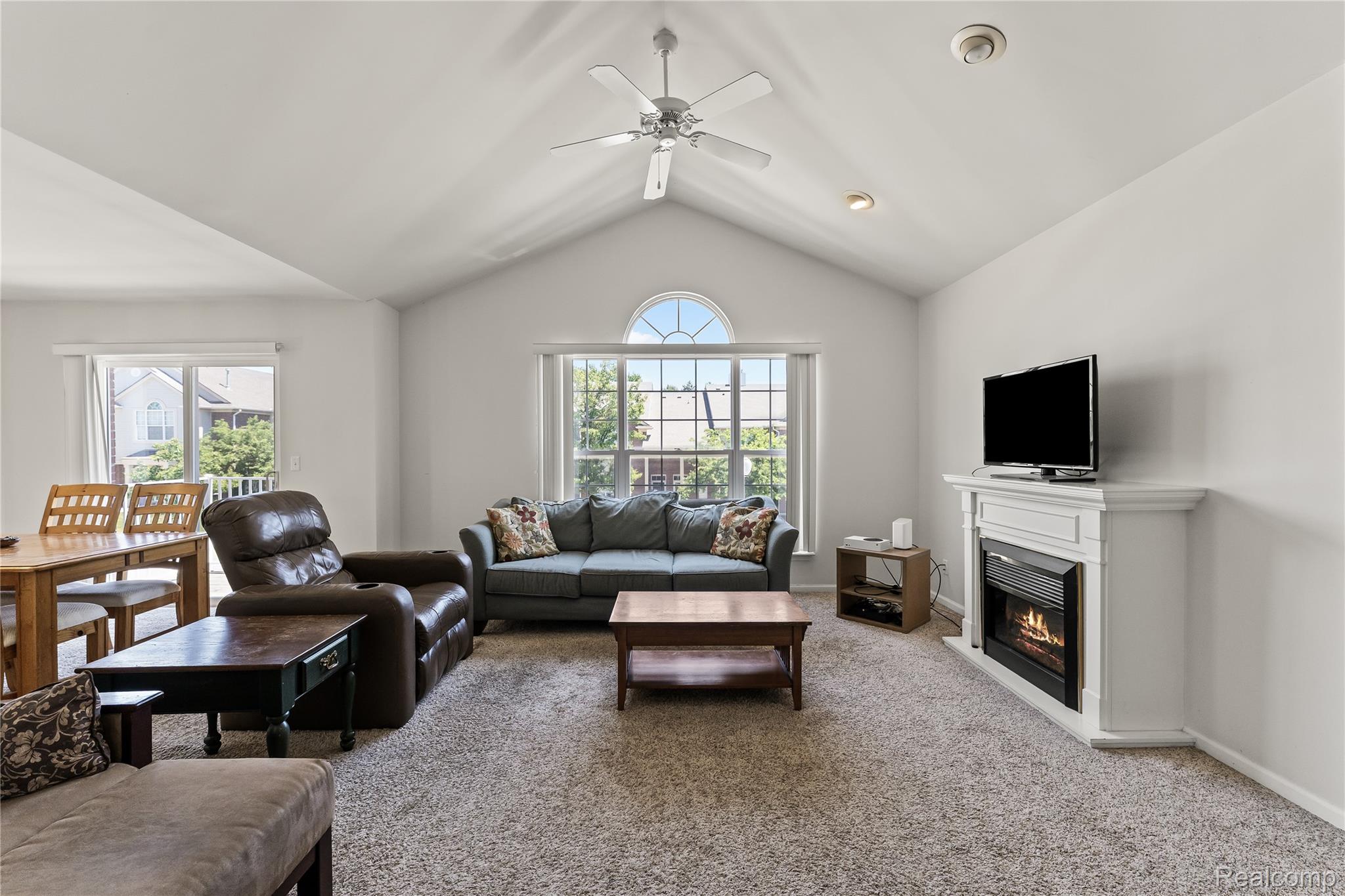 1861 Flagstone Circle Rochester, MI 48307 - Photo 4 of 21 Living area featuring a vaulted ceiling with a ceiling fan, a prominent arched window, and light-colored carpeting