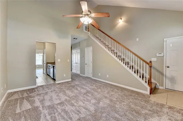 a view of an empty room with stairs and a chandelier fan