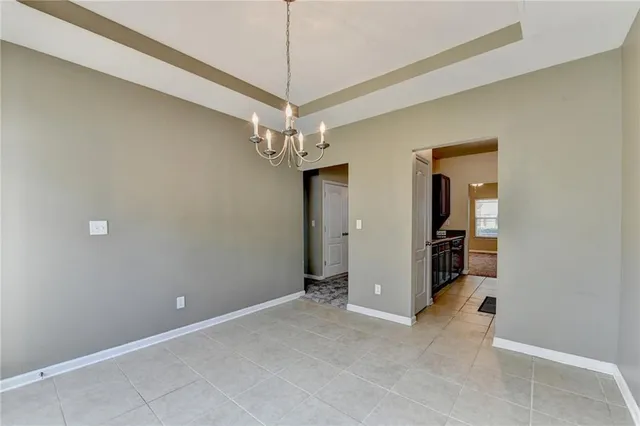en empty room with chandelier fan and kitchen view