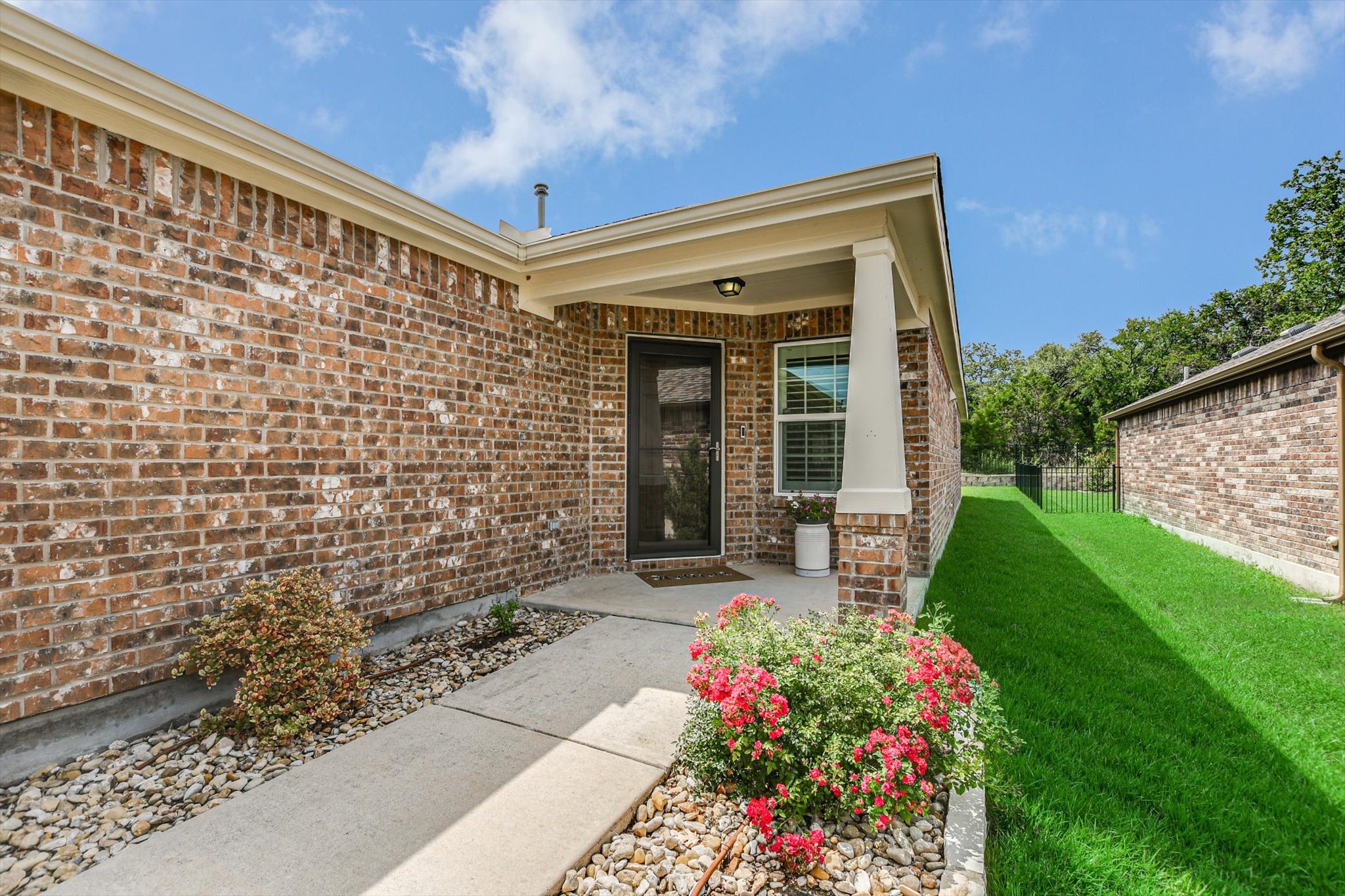 231 Hobby Street Georgetown, TX 78633 - Photo 3 of 29 A welcoming brick facade with a covered entry, lush green lawn, and vibrant landscaping.