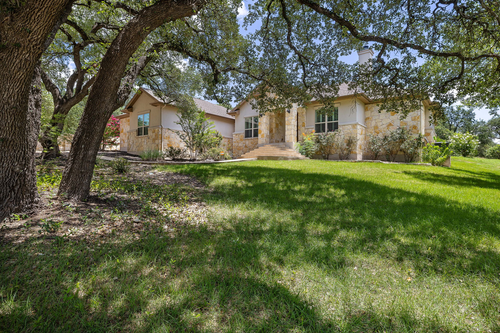 231 Marbella Way Georgetown, TX 78633 - Photo 36 of 40 Mature trees shade this inviting residence, featuring a stone and stucco facade with a grand entryway.