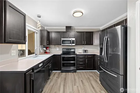 a kitchen with kitchen island granite countertop a refrigerator oven a sink and dishwasher