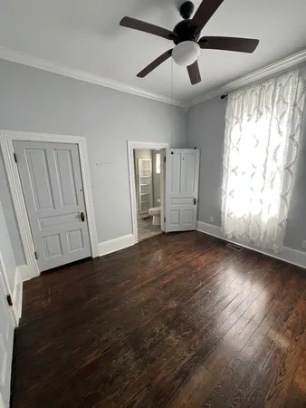 a view of empty room with wooden floor and fan