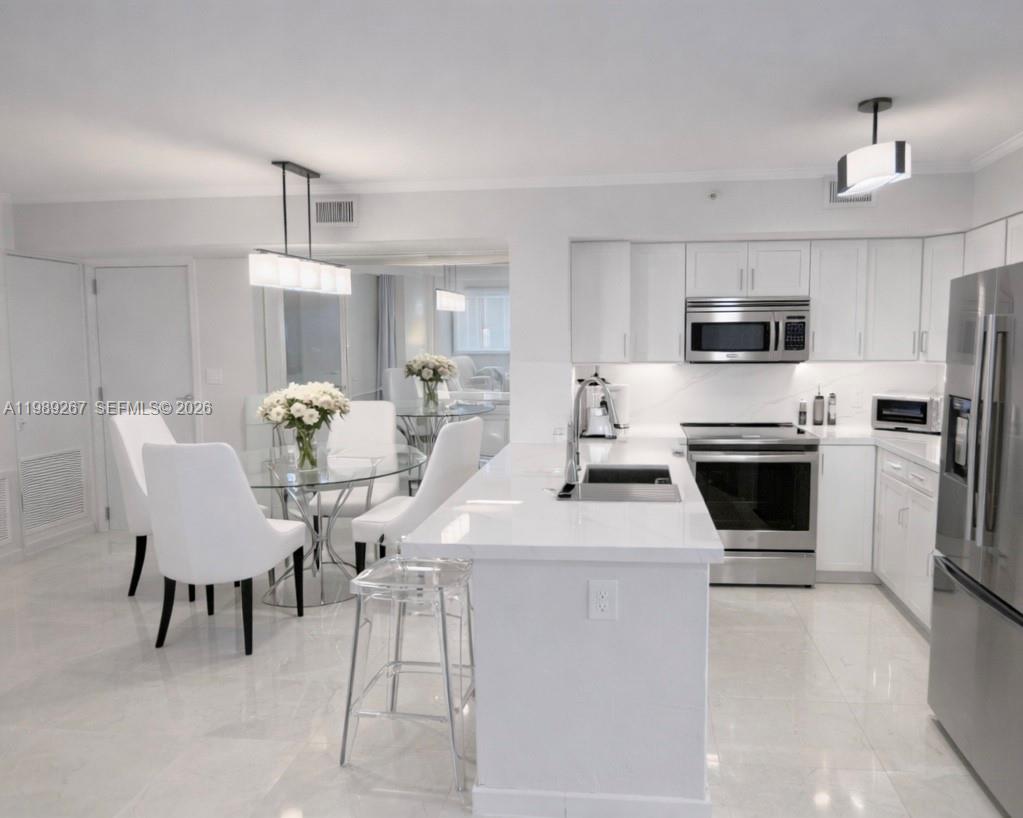 90 Alton Road, Unit 803 Miami Beach, FL 33139 - Photo 9 of 23 a kitchen with kitchen island a stove a microwave a dining table and chairs