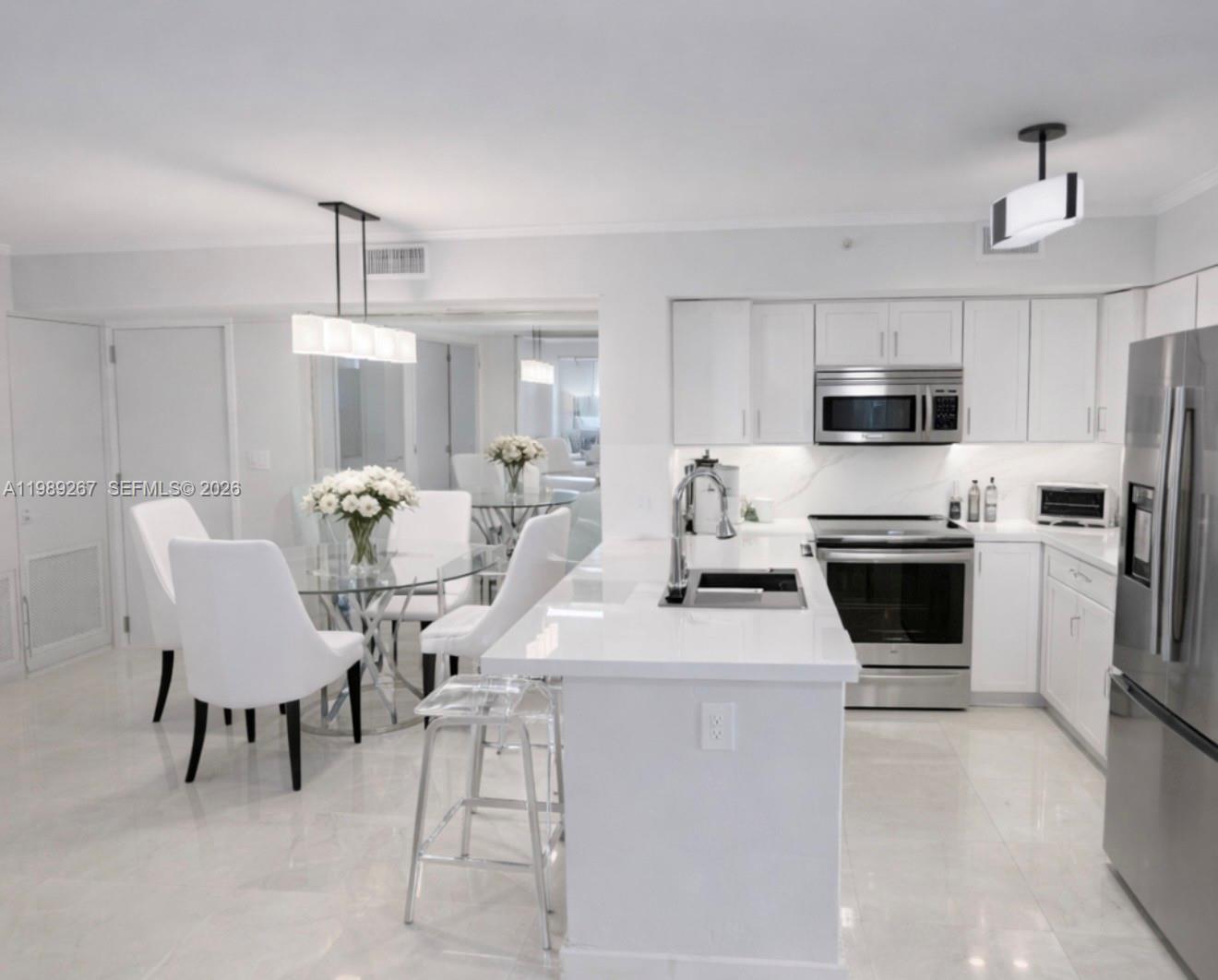90 Alton Road, Unit 803 Miami Beach, FL 33139 - Photo 10 of 23 a kitchen with a white cabinets and chairs and a refrigerator