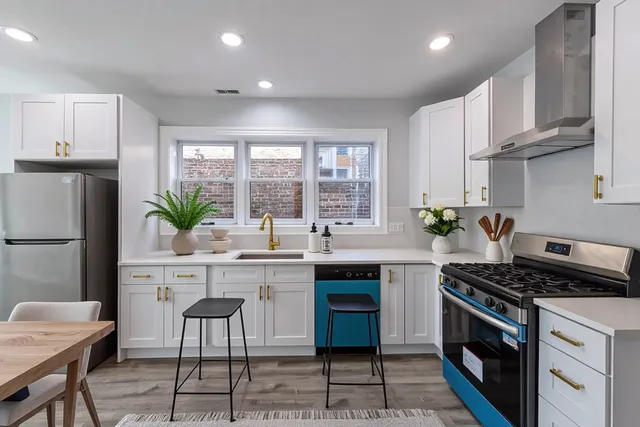 a kitchen with stainless steel appliances granite countertop a stove a sink a refrigerator and a white cabinets