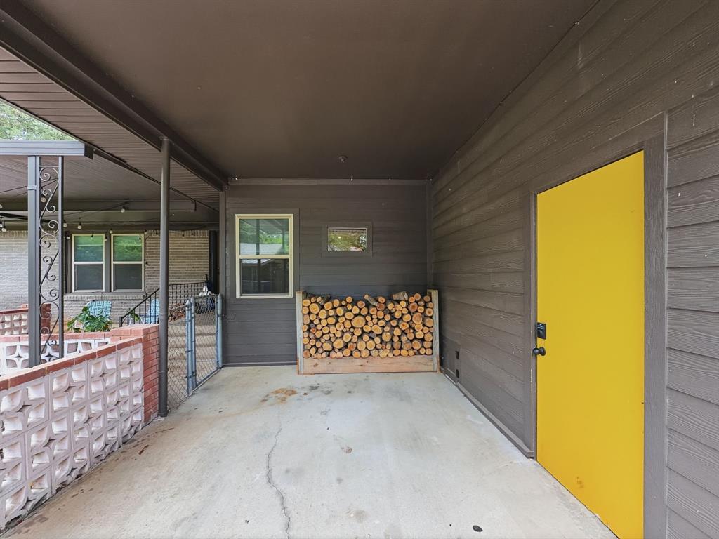 2137 Lenamon Street Waco, TX 76710 - Photo 23 of 29 Covered parking featuring shiplap siding, a bright yellow door, and a decorative breeze block wall